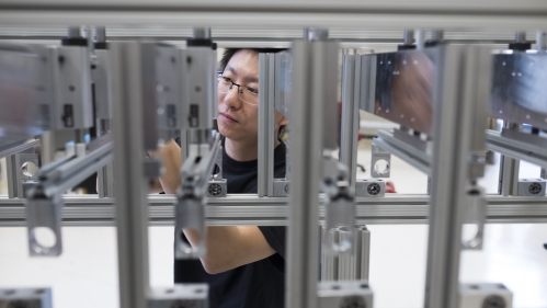 male student with eyeglasses conducting research in industrial engineering laboratory