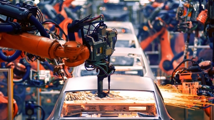 Automotive factory setting with orange robotic arms.