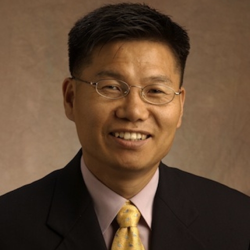 Headshot of a smiling Asian male with eyeglasses and short black hair wearing a dark suit, and yellow ties