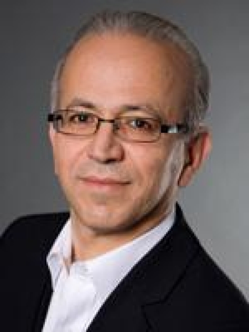 headshot of male short grey hair with eyeglasses and wearing a black suit jacket and white button down shirt