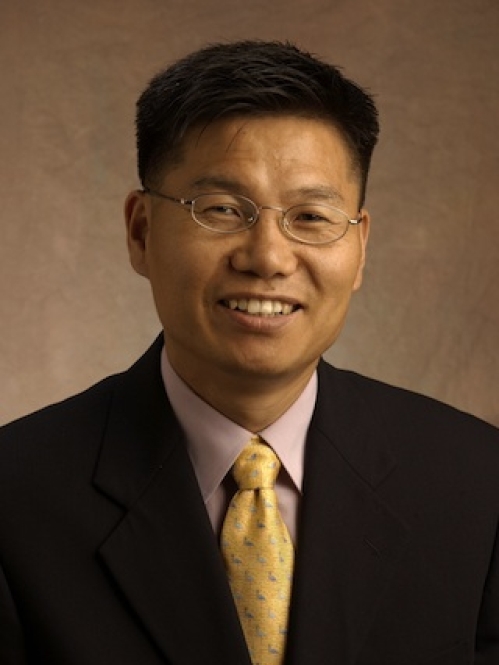 Headshot of a smiling Asian male with eyeglasses and short black hair wearing a dark suit, and yellow ties