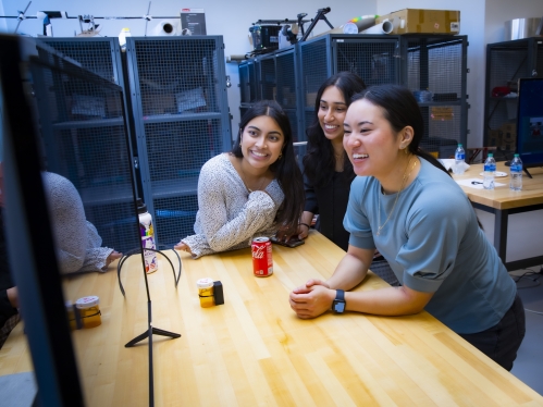 three smiling female students looking at computer secreen