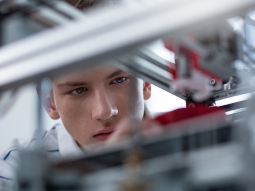 Young adult white male is seen looking through steel bars.