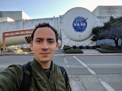 male waering a green jacket standing in front of NASA Unitary Plan Wind Tunnels